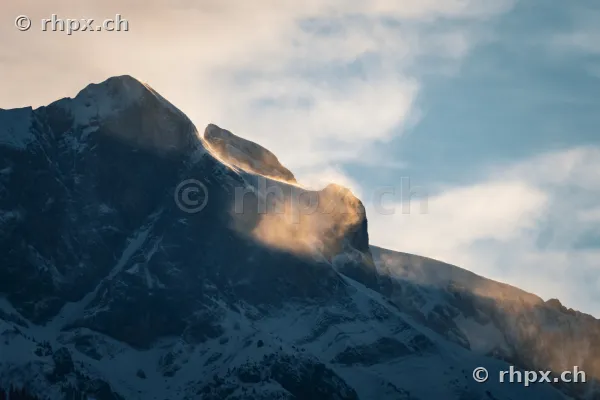 Detailansicht der schneebedeckten Eiger-Nordwand im sanften Licht der Abendsonne mit aufsteigenden Wolken.
