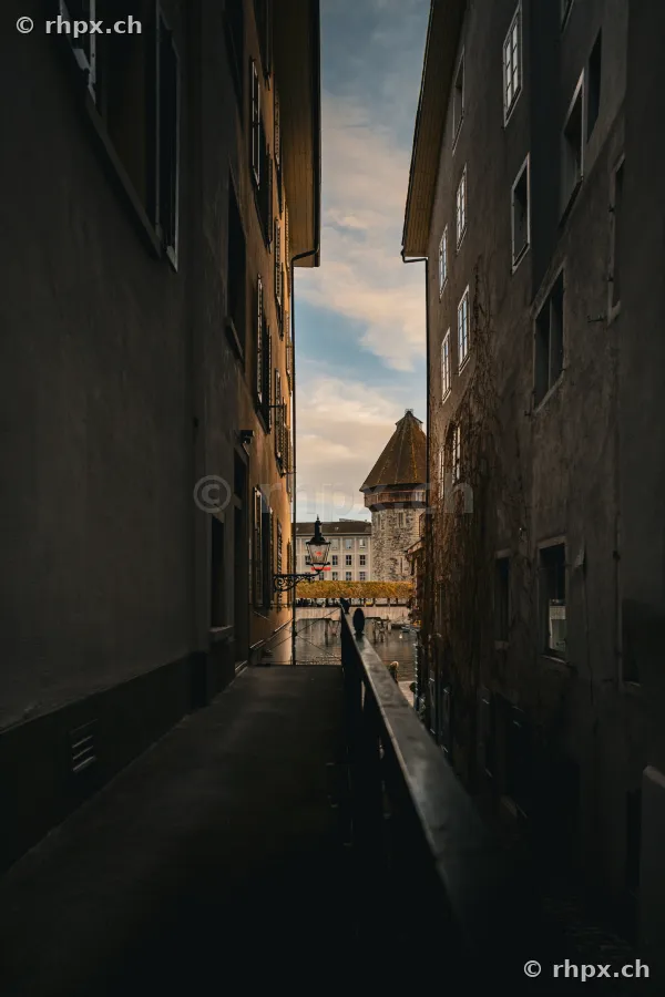 View through a narrow alley towards the Water Tower in Lucerne