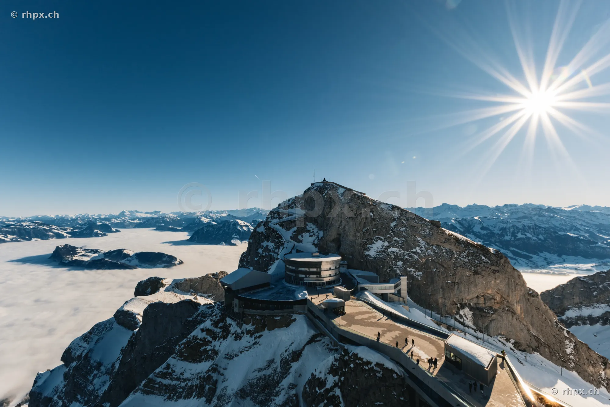 Luftaufnahme des Gipfels Pilatus Kulm bei strahlendem Sonnenschein und Nebeldecke
