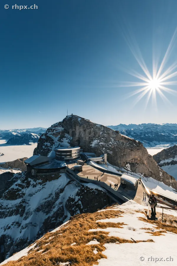Hotel Bellevue and summit area at Mount Pilatus in winter with sun rays