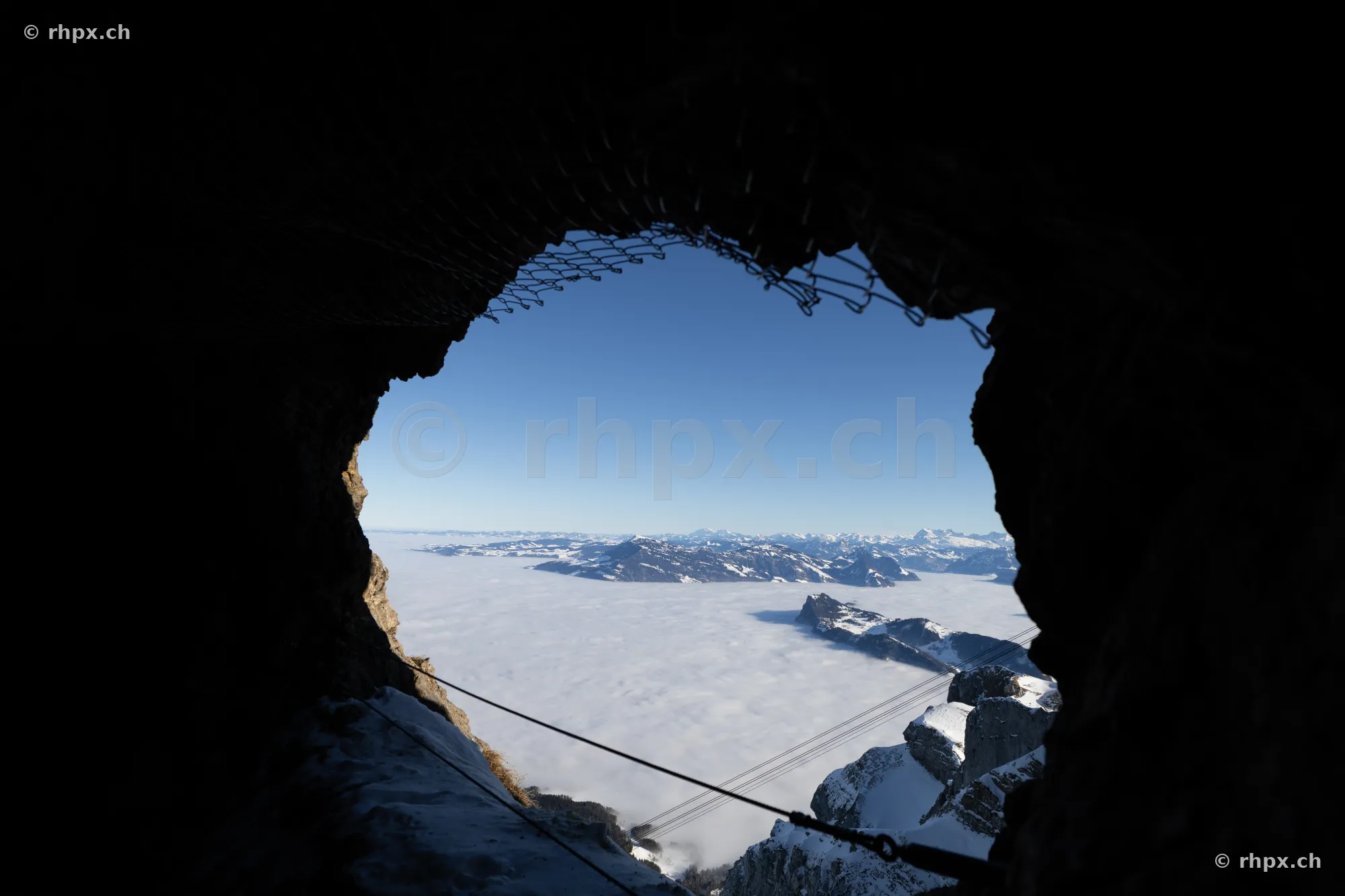 Blick aus einem dunklen Felsdurchgang auf das Nebelmeer über der Zentralschweiz