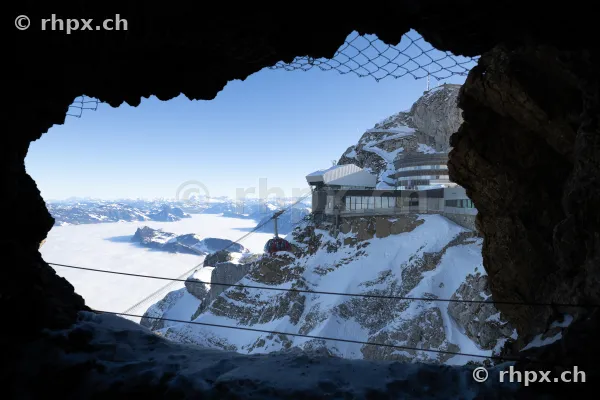 Blick durch eine Felsöffnung auf die Gipfelstation und den Pilatus im Winter