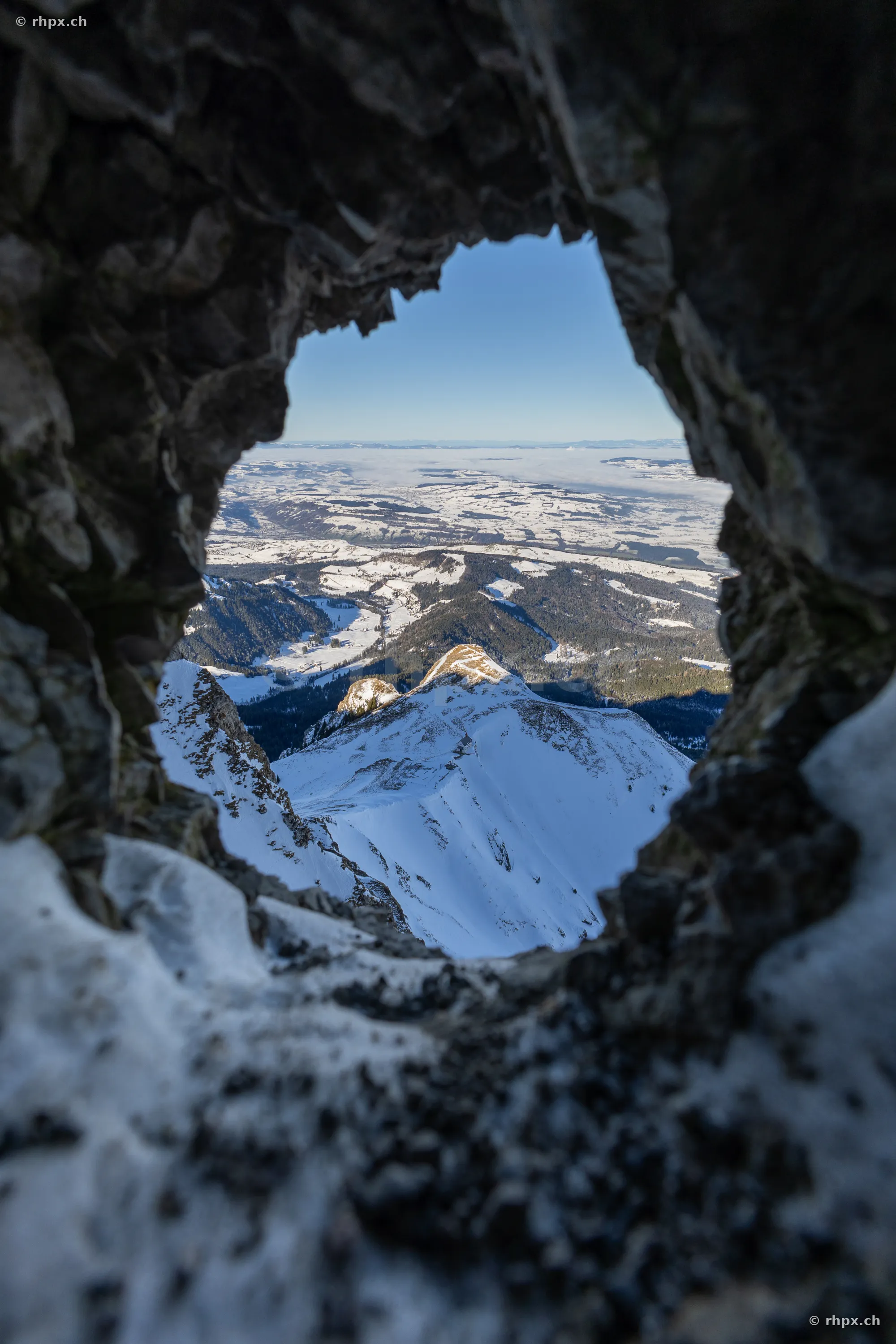Blick durch eine Felsöffnung auf die schneebedeckte Gipfelregion des Pilatus