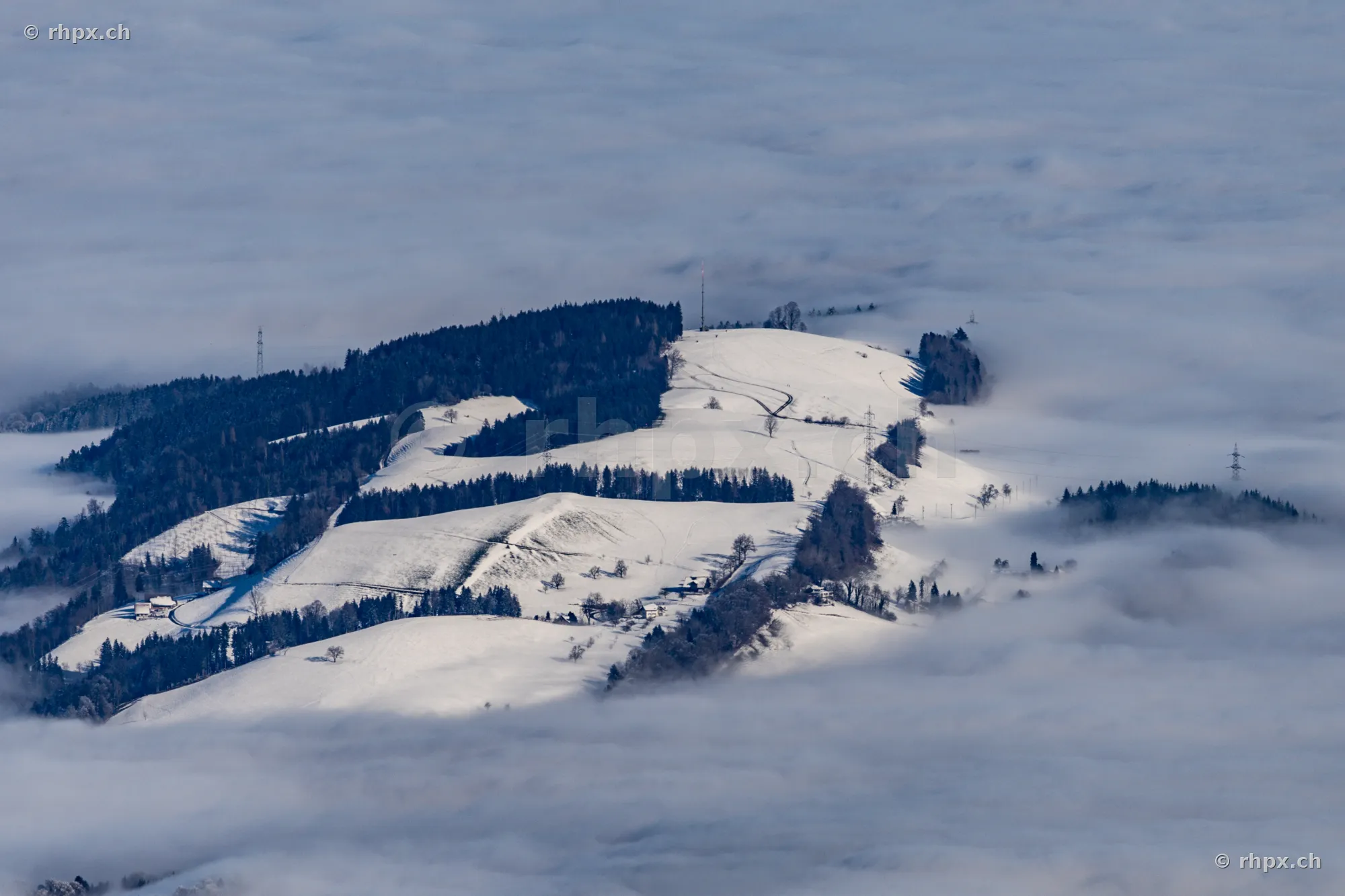 Snow-covered hills in Central Switzerland above a sea of fog