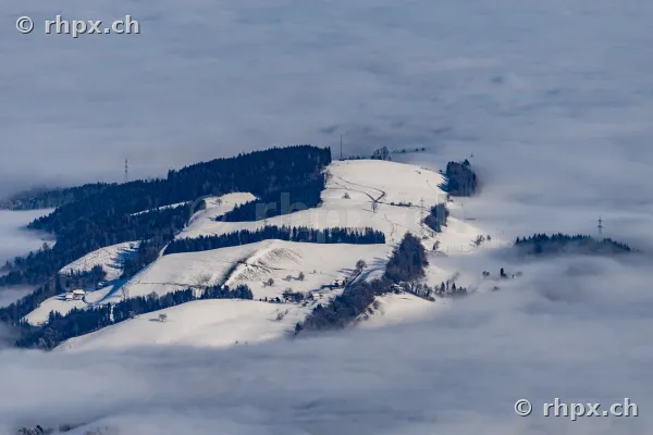 Verschneite Hügellandschaft in der Zentralschweiz oberhalb einer Nebeldecke