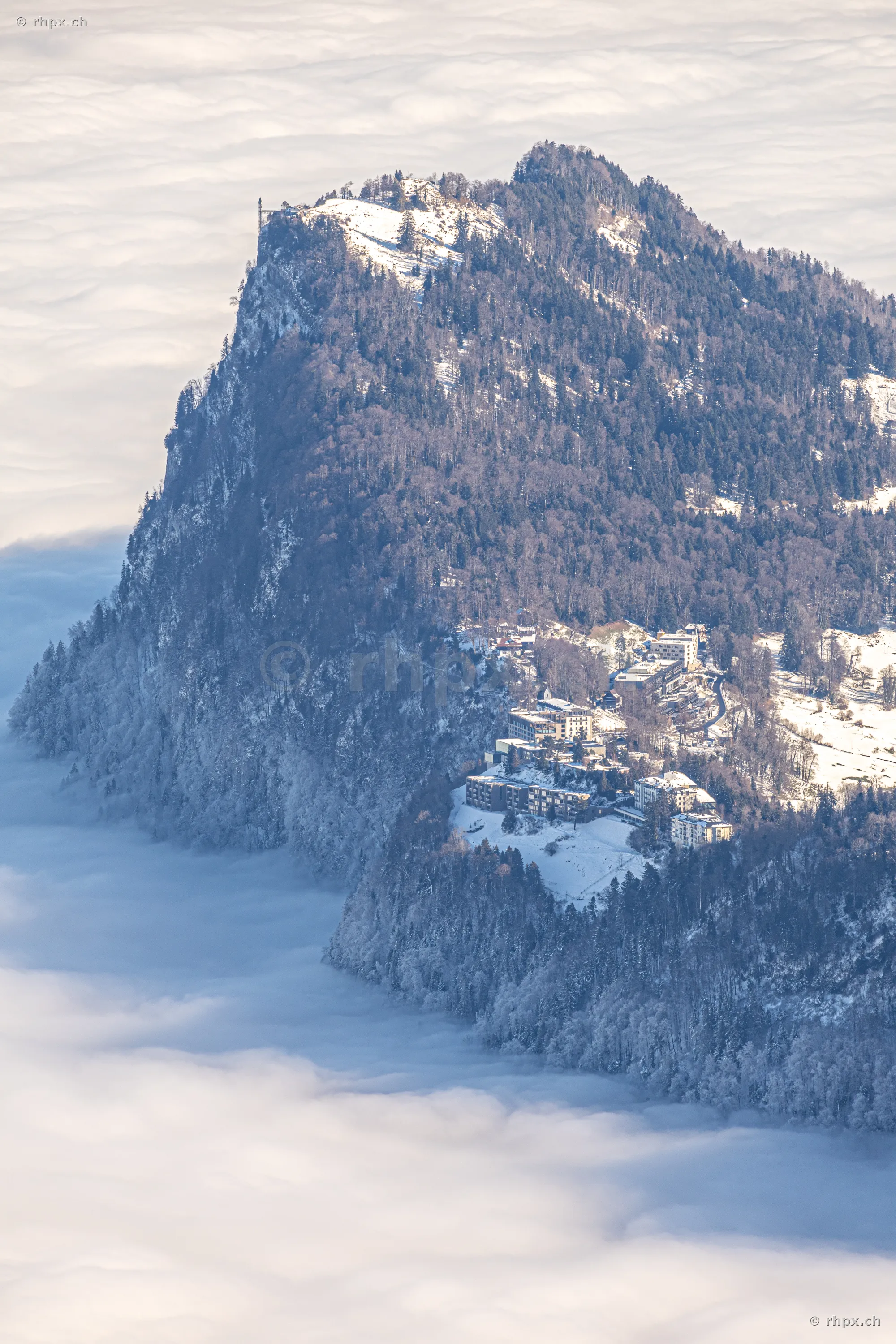 Luftaufnahme des Pilatus Gipfels mit Hotels im Winter über einer geschlossenen Nebeldecke