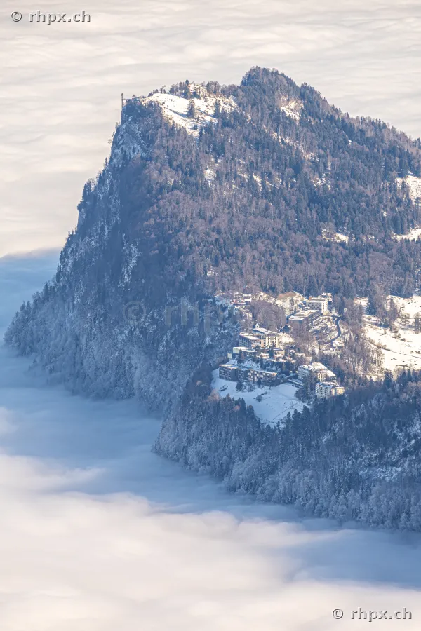 Luftaufnahme des Pilatus Gipfels mit Hotels im Winter über einer geschlossenen Nebeldecke
