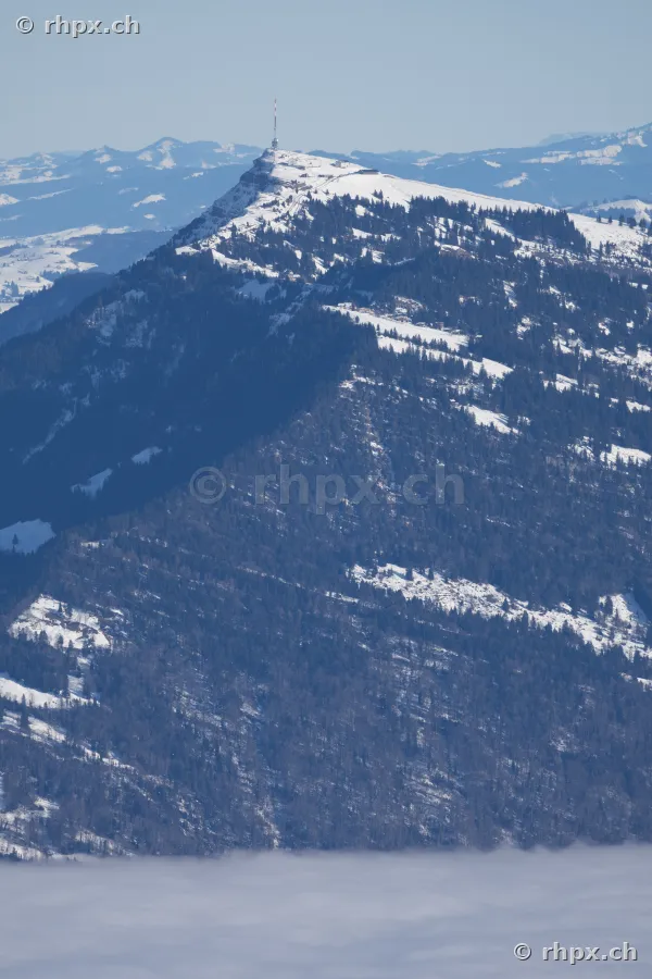 Blick auf den schneebedeckten Gipfel des Rigi mit Sendemast über einer Nebeldecke