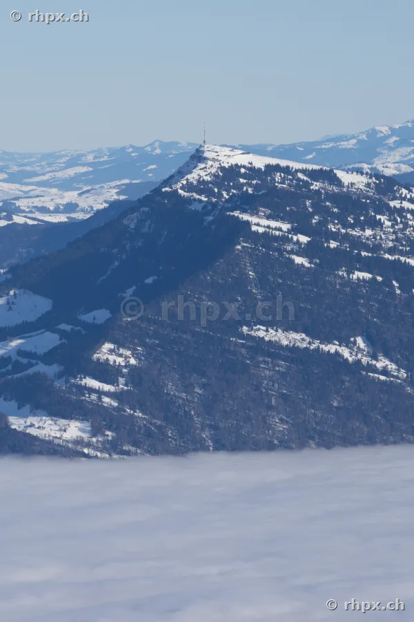 Der verschneite Gipfel der Rigi mit Sendemast ragt aus einer dichten Nebeldecke hervor.