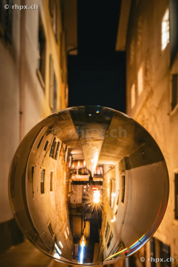 Glass ball in a narrow night-time old town alley in Lucerne