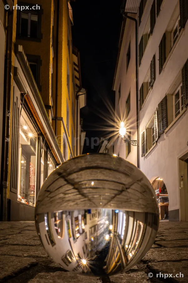 Glass ball on cobblestones in a narrow alley in the old town of Lucerne at night