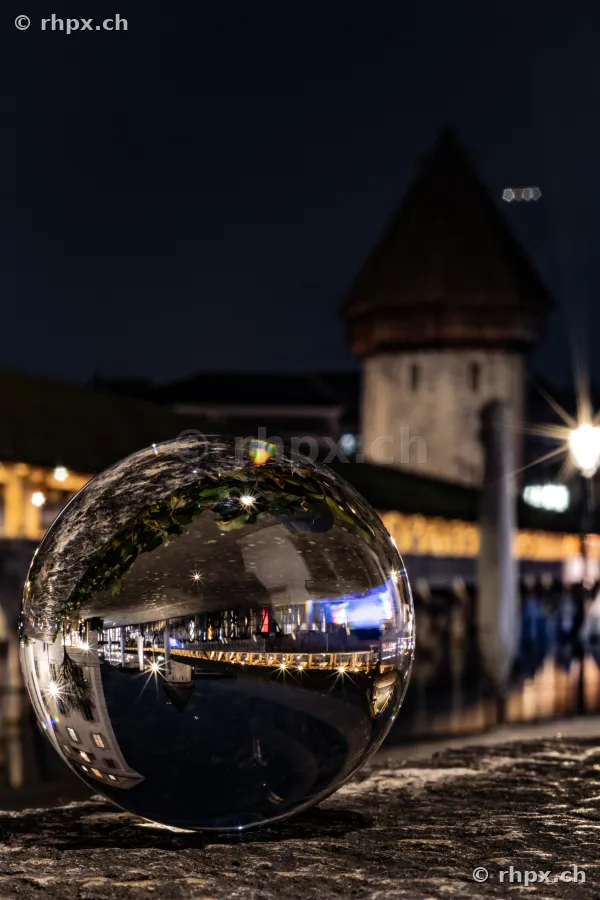 The night view of Chapel Bridge in Lucerne reflected in a glass sphere on a wall