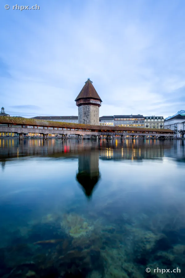 Chapel Bridge with water tower in Lucerne at dusk with reflecting river Reuss