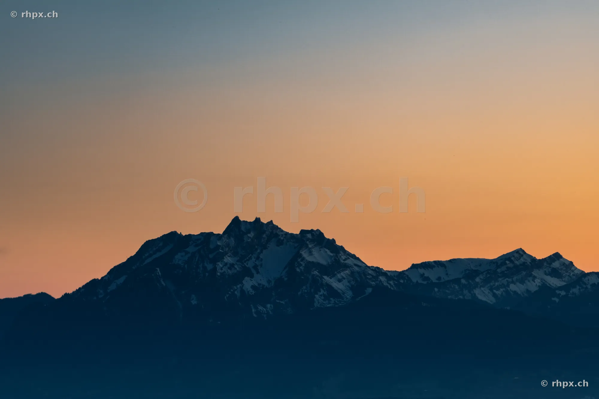 Dunkle Silhouette des Berges Pilatus vor einem orangefarbenen Abendhimmel