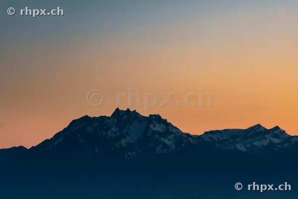 Dunkle Silhouette des Berges Pilatus vor einem orangefarbenen Abendhimmel