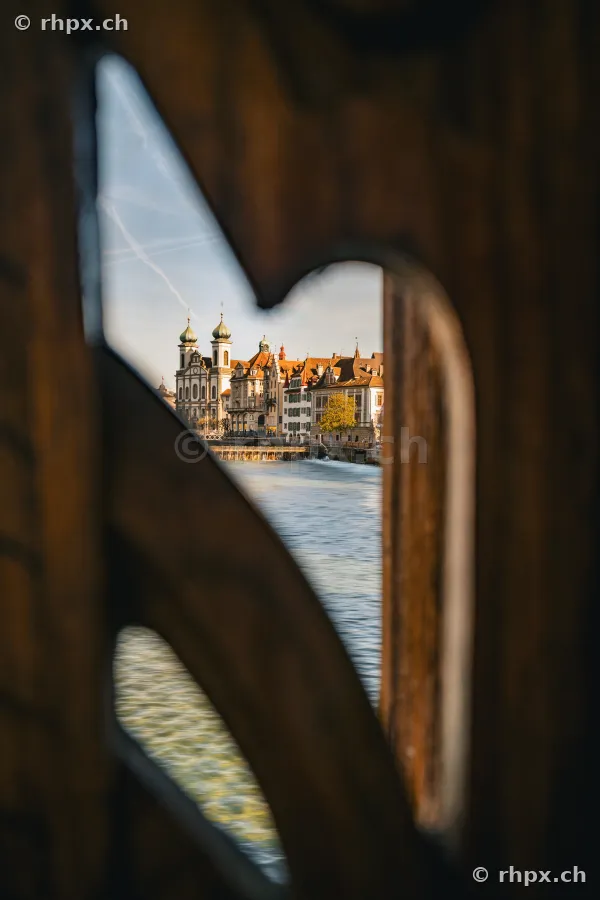 View through the wooden gable decorations of the Chapel Bridge towards the Jesuit Church and the Reuss river in Lucerne.