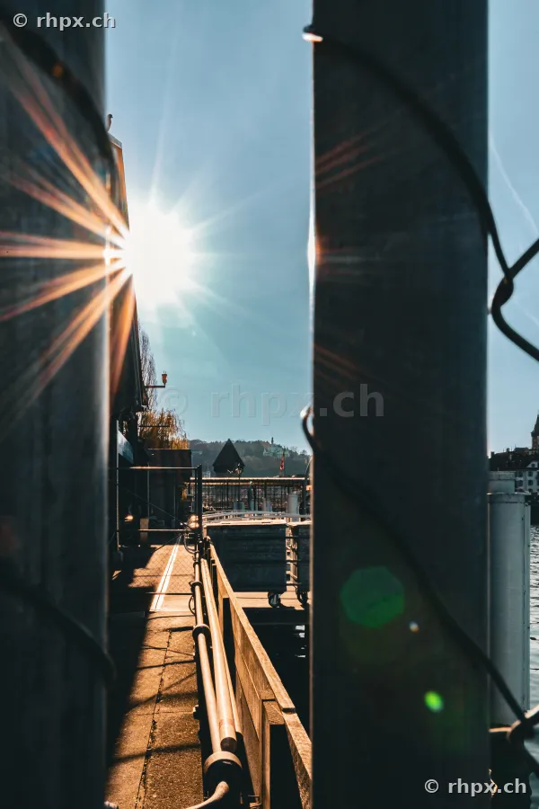 View through two vertical pillars onto a pier at Lake Lucerne in backlight.