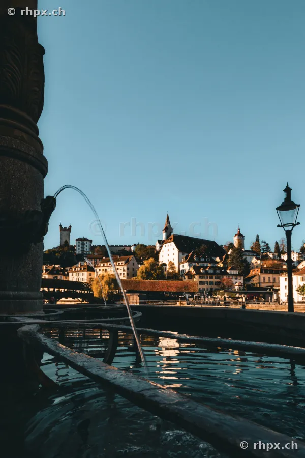 Historic fountain at the river Reuss with a view of Lucerne's old town