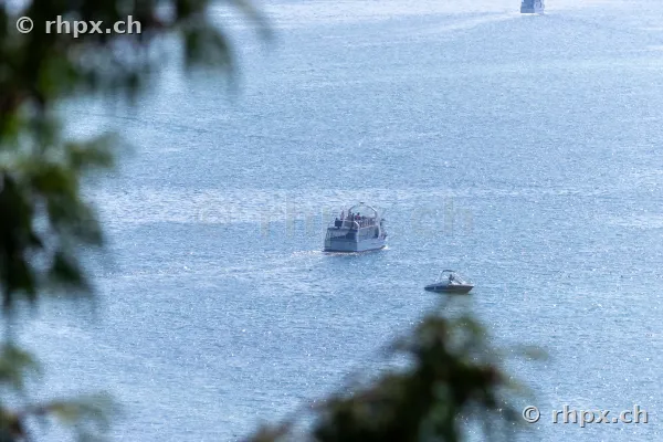 A passenger boat and a small motorboat on the blue shimmering Lake Lucerne.