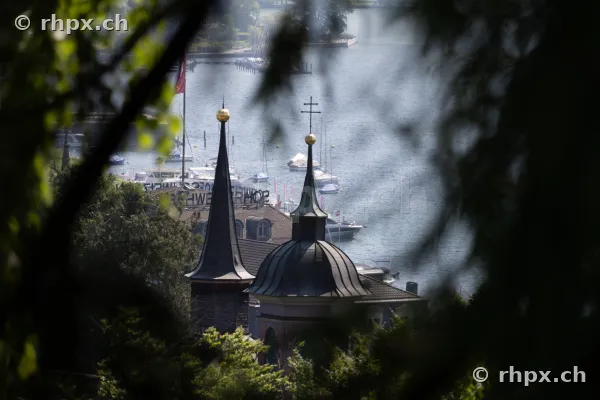 View through foliage towards church spires and Lake Lucerne