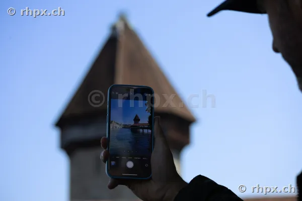 Person fotografiert den Wasserturm der Kapellbrücke in Luzern mit einem Smartphone