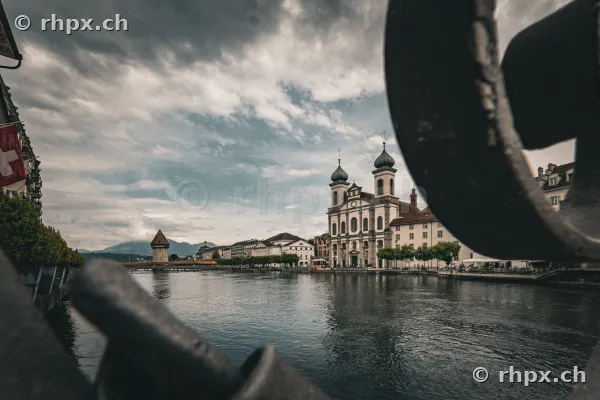 View of the Hofkirche and the Reuss river in Lucerne with a railing in the foreground