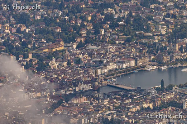Aerial view of Lucerne city with Reuss river and old town, partially covered by fog.