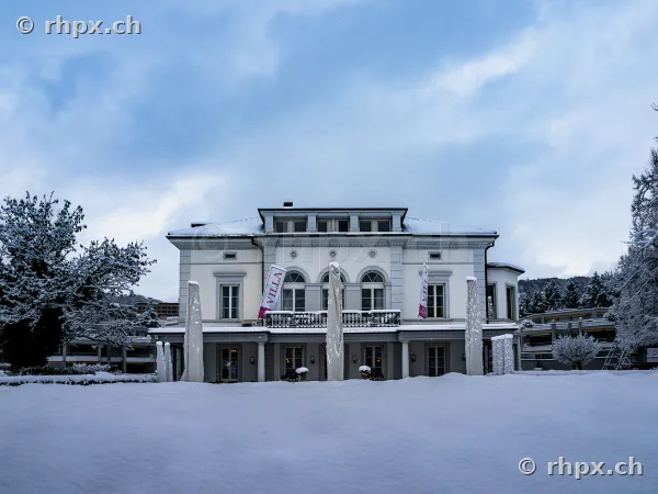Die verschneite Fassade der Villa Schweizerhof in Luzern unter einem bewölkten Winterhimmel