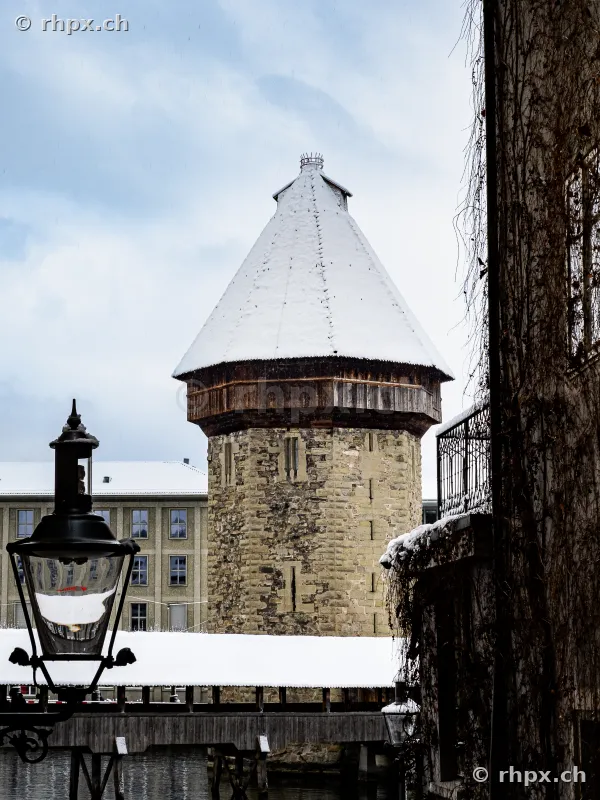 The snow-covered Water Tower in Lucerne with a street lamp in the foreground