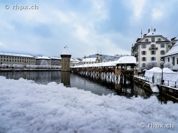 View of the snow-covered Chapel Bridge with water tower in Lucerne