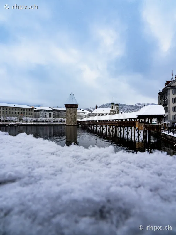 The snow-covered Chapel Bridge with Water Tower in Lucerne on a winter day