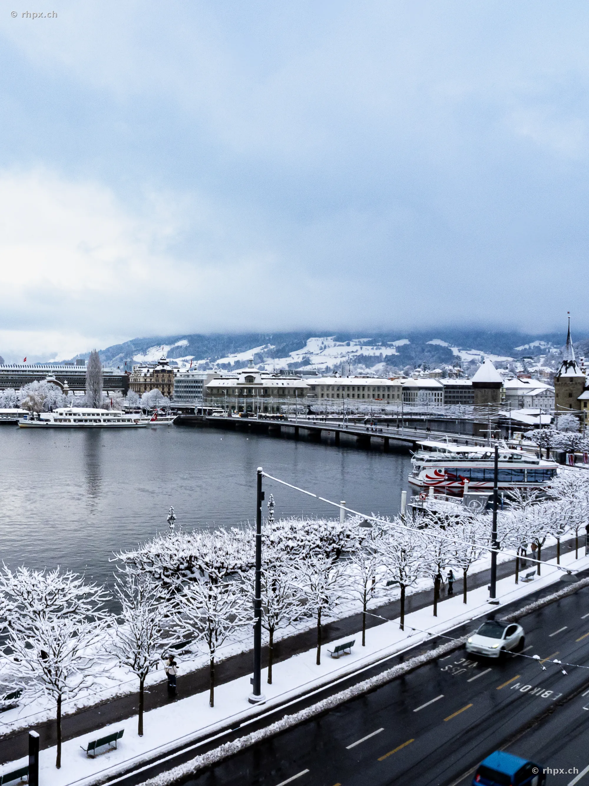 Blick über das verschneite Luzerner Seebecken und das Hotel Schweizerhof bei bewölktem Himmel