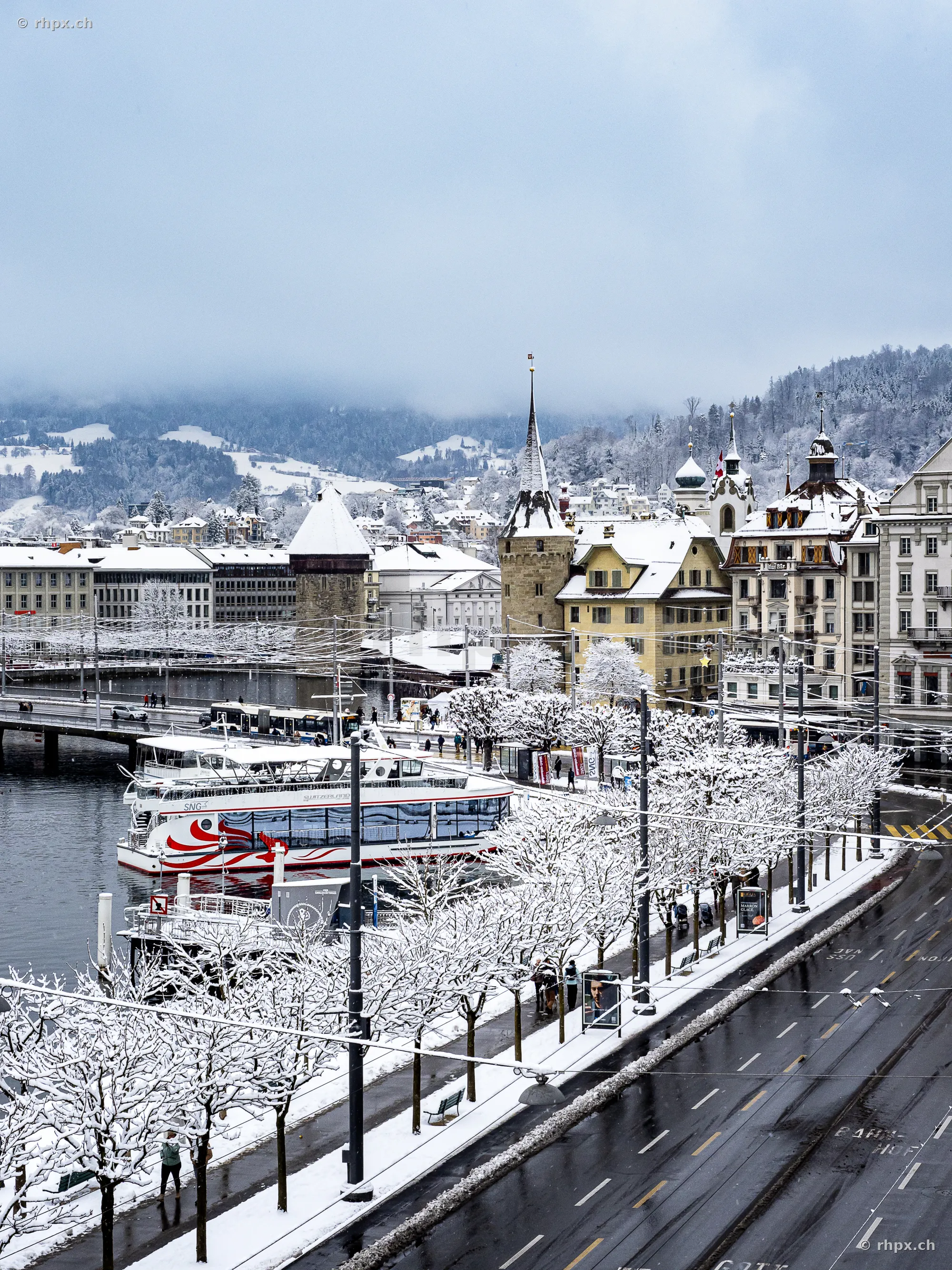 Snowy waterfront promenade and boats in front of Hotel Schweizerhof in Lucerne in winter
