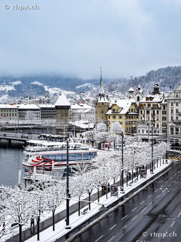 Verschneite Uferpromenade und Schiffe vor dem Hotel Schweizerhof in Luzern im Winter