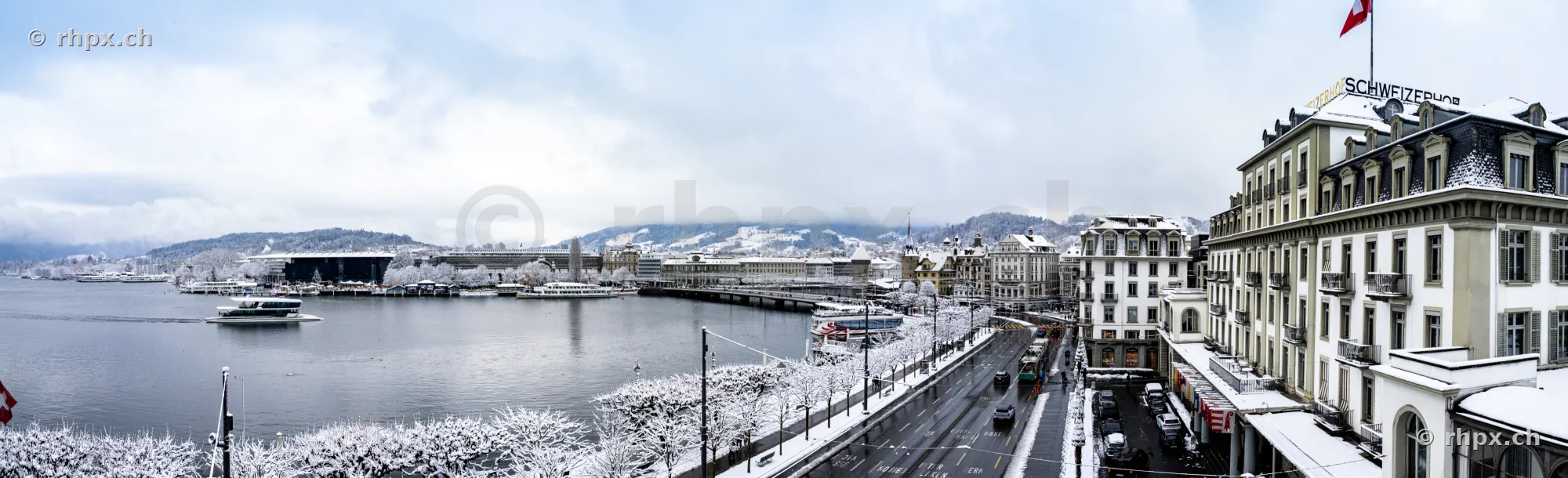 Blick auf das verschneite Luzerner Seebecken mit Hotel Schweizerhof bei bewölktem Himmel