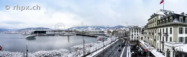 Blick auf das verschneite Luzerner Seebecken mit Hotel Schweizerhof bei bewölktem Himmel
