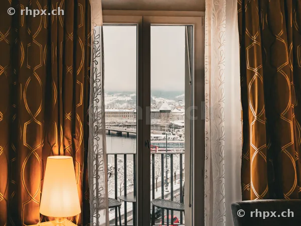 Blick durch ein Fenster aus dem Hotel Schweizerhof auf die verschneite Stadt Luzern