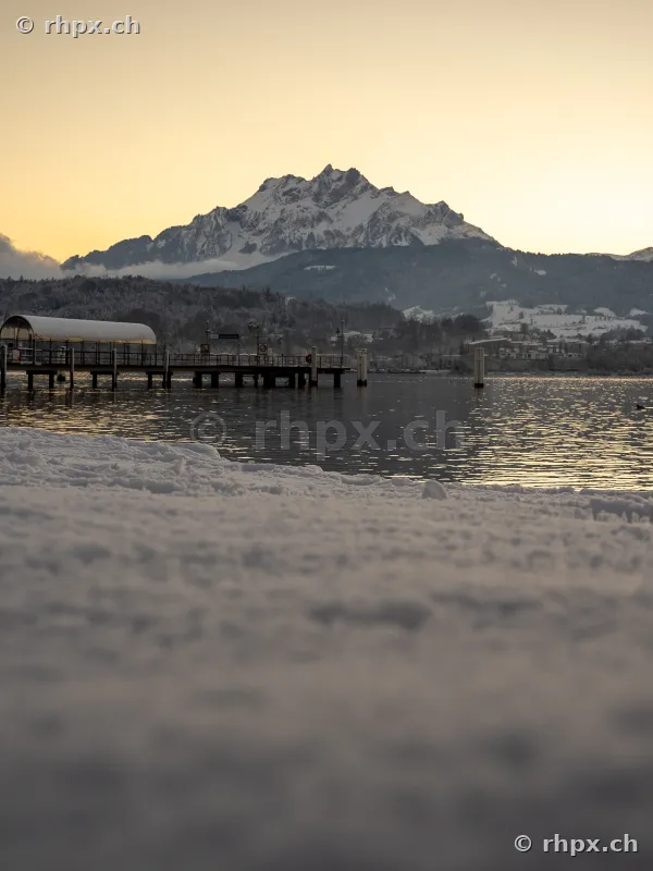 View of the snow-covered Mount Pilatus with a boat pier on Lake Lucerne