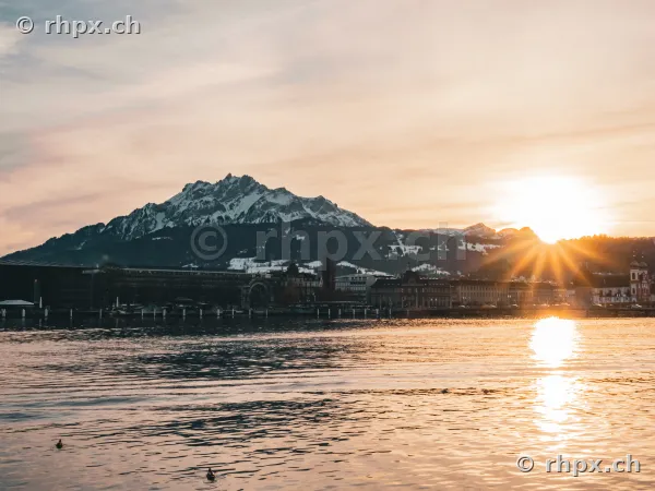 Blick über den Vierwaldstättersee auf den schneebedeckten Pilatus während des Sonnenuntergangs.