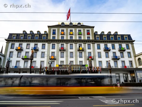 Hotel Schweizerhof Luzern mit bunten Dekorationen an der Fassade und einem vorbeifahrenden Bus im Vordergrund