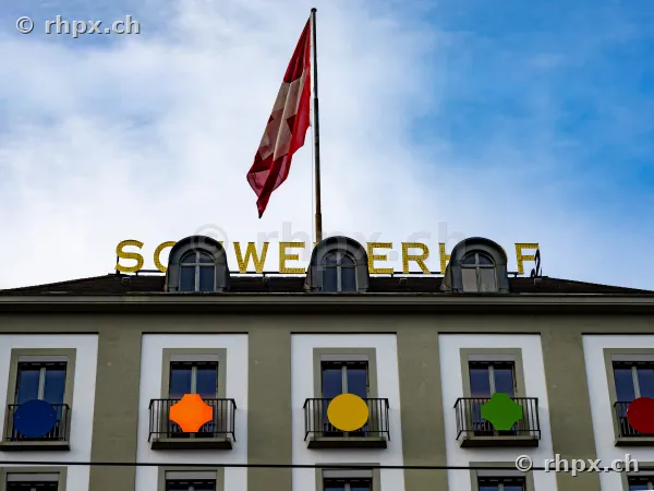 Fassade des Hotels Schweizerhof in Luzern mit wehender Schweizer Flagge auf dem Dach.