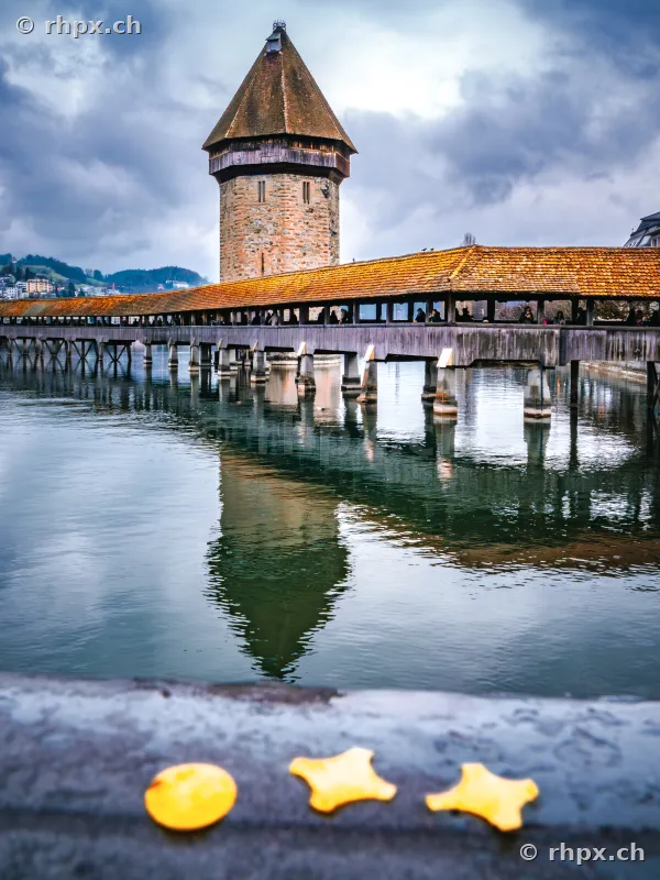 Kapellbrücke mit Wasserturm in Luzern, im Vordergrund liegen Konfetti auf einer Mauer.