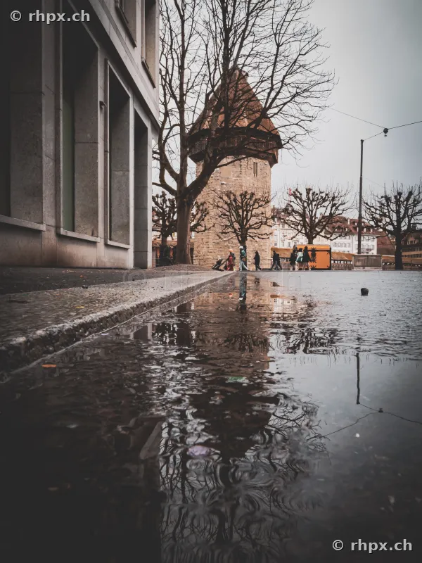 The Wasserturm in Lucerne reflected in a puddle on the ground