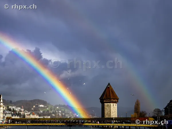 Rainbow over the Chapel Bridge and the Water Tower in Lucerne against a dark cloudy sky
