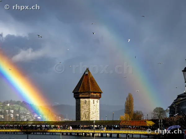 The water tower at the Chapel Bridge in Lucerne with a rainbow in the background
