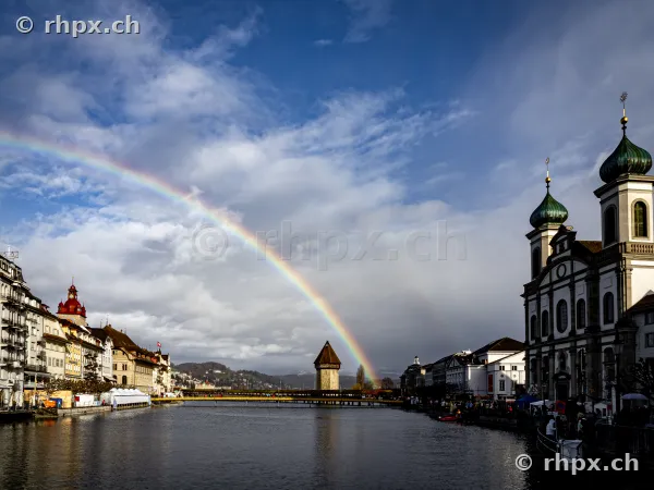Rainbow over the Reuss river with a view of the Chapel Bridge and the Jesuit Church in Lucerne