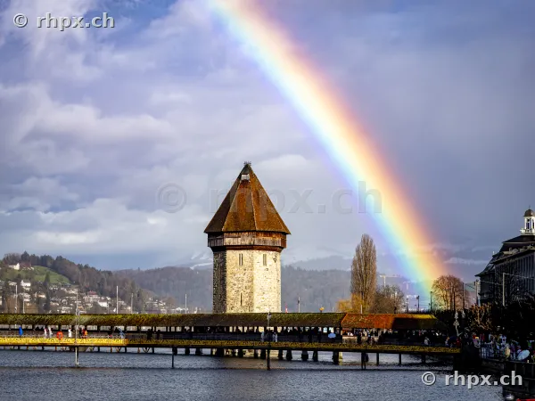Water tower of the Chapel Bridge in Lucerne with a rainbow in the cloudy sky