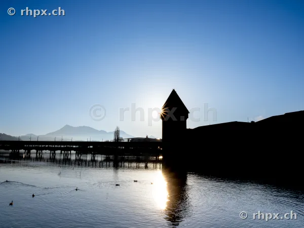 Silhouette of the Water Tower and Chapel Bridge in Lucerne against the setting sun