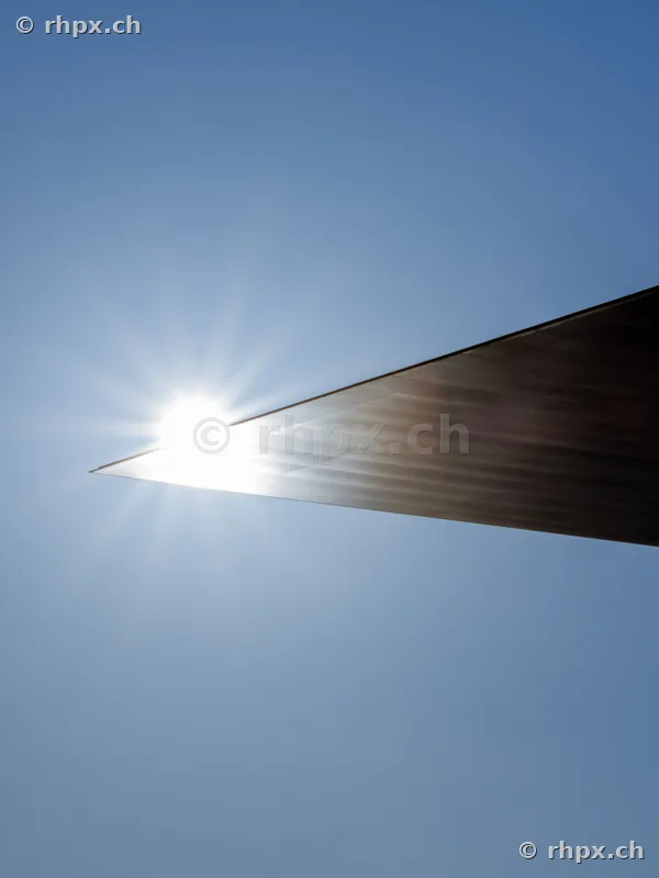 Die Sonne scheint hinter der scharfen Kante eines modernen architektonischen Daches hervor.