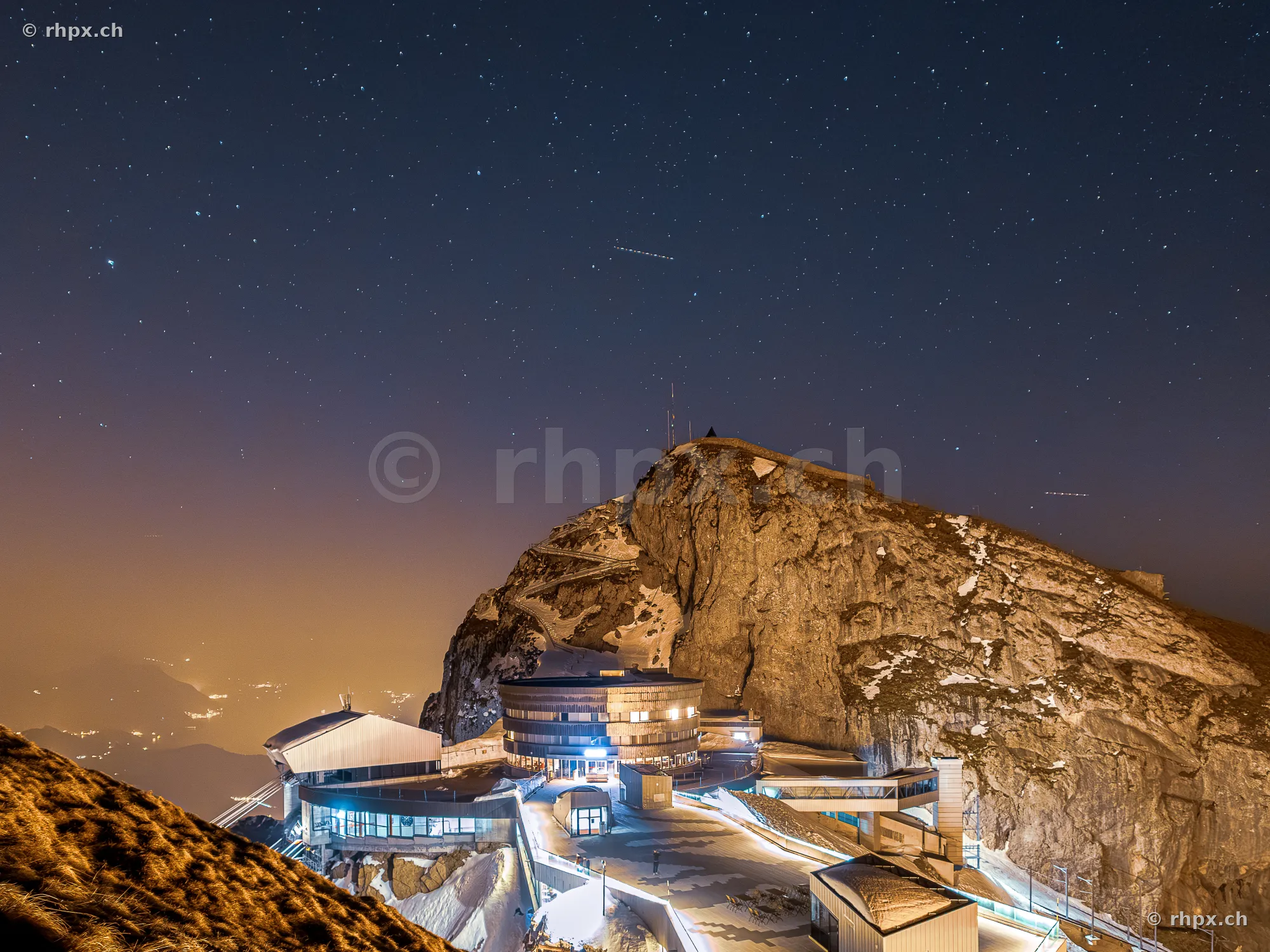 The illuminated summit of Mount Pilatus at night under a starry sky